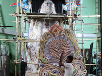 An artist carries a crown made with a thermocol sheet before decorating an idol of the Hindu goddess Kali inside a ''pandal'' (a temporary p...