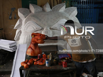 An artisan prepares decoration items used to decorate a ''pandal'' (a temporary platform), a decorated structure next to an idol of the Hind...