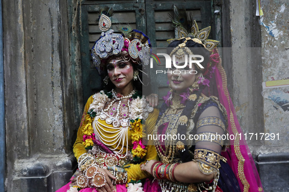 Artists rest after performing an inauguration program next to a ''pandal'' (a temporary platform), a decorated structure, next to an idol of...