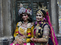 Artists rest after performing an inauguration program next to a ''pandal'' (a temporary platform), a decorated structure, next to an idol of...