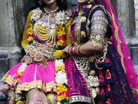 Artists rest after performing an inauguration program next to a ''pandal'' (a temporary platform), a decorated structure, next to an idol of...