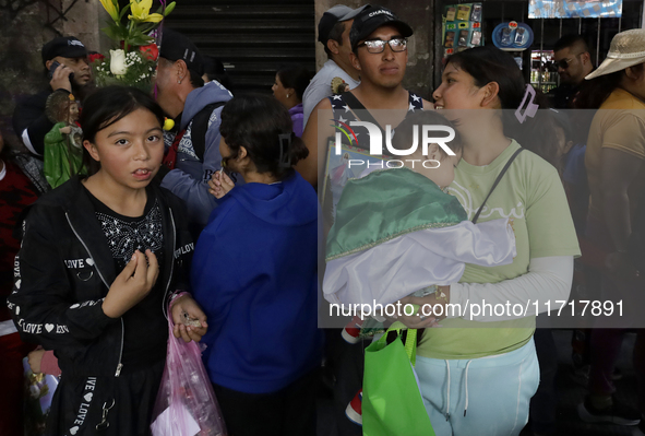 A woman carries a minor dressed as Saint Jude Thaddeus outside the Church of San Hipolito in Mexico City, Mexico, on October 28, 2024. The c...