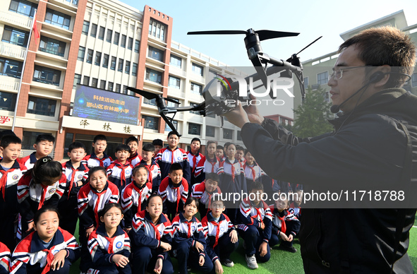 A staff member introduces a drone to primary school students in Handan, China, on October 29, 2024. 