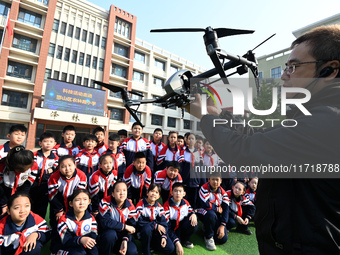 A staff member introduces a drone to primary school students in Handan, China, on October 29, 2024. (