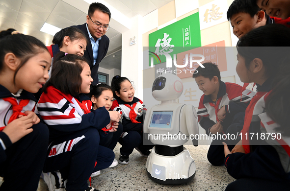 Primary school students talk and interact with a robot in Handan, China, on October 29, 2024. 