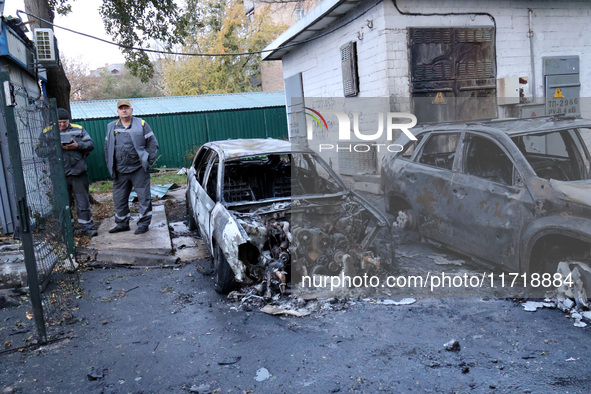 Municipal workers stand by cars in the Solomianskyi district damaged by a Russian drone attack in Kyiv, Ukraine, on October 29, 2024. Six pe...