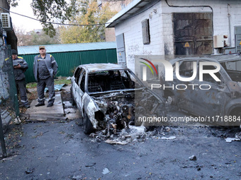 Municipal workers stand by cars in the Solomianskyi district damaged by a Russian drone attack in Kyiv, Ukraine, on October 29, 2024. Six pe...