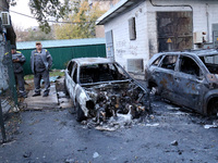 Municipal workers stand by cars in the Solomianskyi district damaged by a Russian drone attack in Kyiv, Ukraine, on October 29, 2024. Six pe...