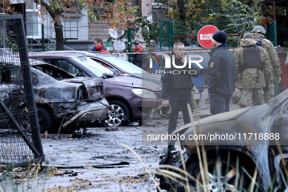 Law enforcers stand by cars in the Solomianskyi district damaged by a Russian drone attack in Kyiv, Ukraine, on October 29, 2024. Six people...