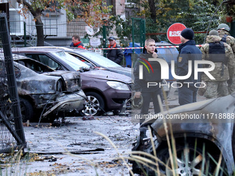 Law enforcers stand by cars in the Solomianskyi district damaged by a Russian drone attack in Kyiv, Ukraine, on October 29, 2024. Six people...