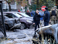 Law enforcers stand by cars in the Solomianskyi district damaged by a Russian drone attack in Kyiv, Ukraine, on October 29, 2024. Six people...