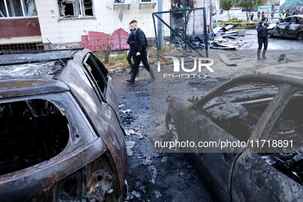 People walk past burnt-out cars in the Solomianskyi district after a Russian drone attack in Kyiv, Ukraine, on October 29, 2024. Six people...