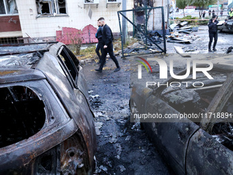 People walk past burnt-out cars in the Solomianskyi district after a Russian drone attack in Kyiv, Ukraine, on October 29, 2024. Six people...