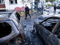 People walk past burnt-out cars in the Solomianskyi district after a Russian drone attack in Kyiv, Ukraine, on October 29, 2024. Six people...