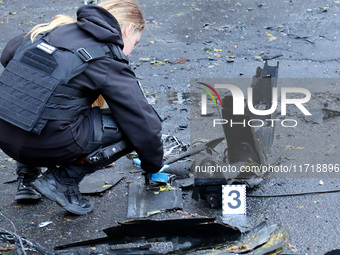 A police officer studies the fragments of a Russian UAV in the Solomianskyi district after a Russian drone attack in Kyiv, Ukraine, on Octob...