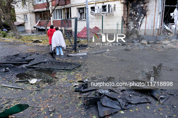 People stand among the debris and look at an apartment block in the Solomianskyi district damaged by a Russian drone attack in Kyiv, Ukraine...