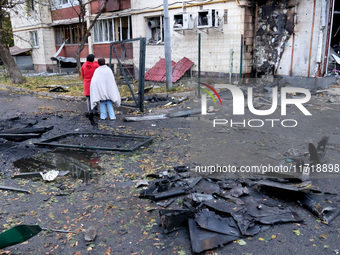 People stand among the debris and look at an apartment block in the Solomianskyi district damaged by a Russian drone attack in Kyiv, Ukraine...