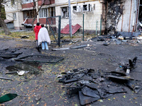 People stand among the debris and look at an apartment block in the Solomianskyi district damaged by a Russian drone attack in Kyiv, Ukraine...