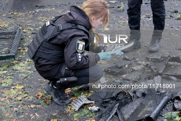 A police officer studies the fragments of a Russian UAV in the Solomianskyi district after a Russian drone attack in Kyiv, Ukraine, on Octob...