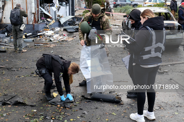 Law enforcers pick up the fragments of a Russian UAV in the Solomianskyi district after a Russian drone attack in Kyiv, Ukraine, on October...