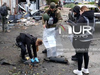 Law enforcers pick up the fragments of a Russian UAV in the Solomianskyi district after a Russian drone attack in Kyiv, Ukraine, on October...