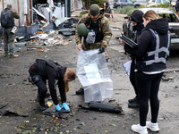 Law enforcers pick up the fragments of a Russian UAV in the Solomianskyi district after a Russian drone attack in Kyiv, Ukraine, on October...