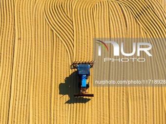 Workers operate machines to harvest rice at Baima Lake farm in Huai'an, China, on October 29, 2024. (