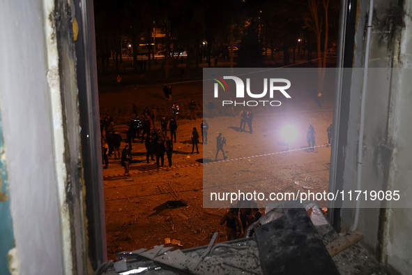 A shattered window frames people in the street outside the 1930s Derzhprom building, which a Russian guided bomb damages in central Kharkiv,...