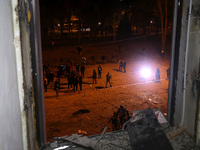 A shattered window frames people in the street outside the 1930s Derzhprom building, which a Russian guided bomb damages in central Kharkiv,...