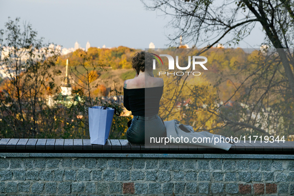 A woman in an off-shoulder top sits on a bench in Peizazhna Alley in Kyiv, Ukraine, on October 28, 2024. 