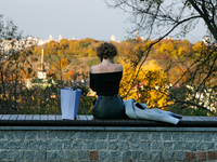 A woman in an off-shoulder top sits on a bench in Peizazhna Alley in Kyiv, Ukraine, on October 28, 2024. (