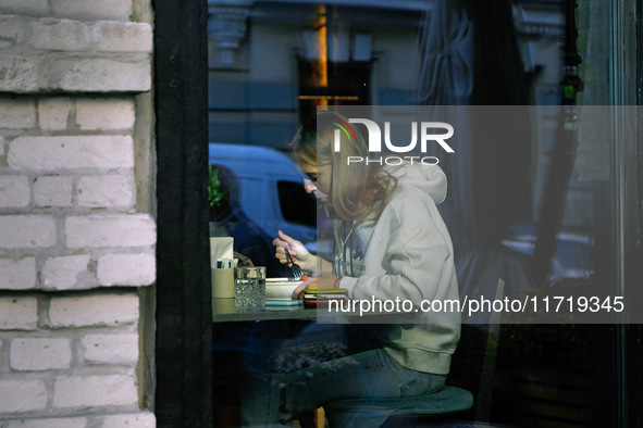 A woman eats in a cafe as seen through a window in Kyiv, Ukraine, on October 28, 2024. 