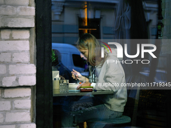 A woman eats in a cafe as seen through a window in Kyiv, Ukraine, on October 28, 2024. (