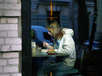 A woman eats in a cafe as seen through a window in Kyiv, Ukraine, on October 28, 2024. (