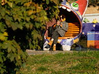 A woman in sunglasses sits on a bench covered in mosaics in Peizazhna Alley in Kyiv, Ukraine, on October 28, 2024. (