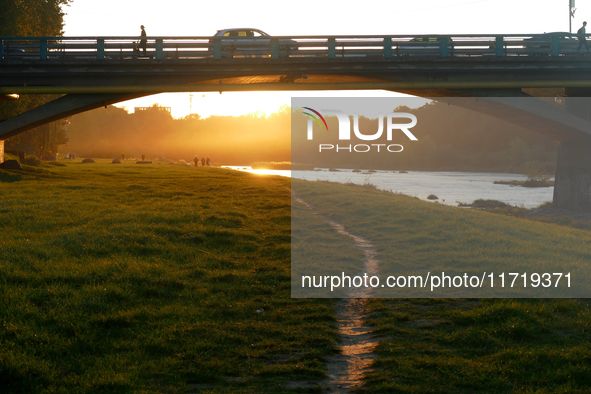 Cars and people are on the bridge across the Uzh River at sunset in Uzhhorod, Ukraine, on October 24, 2024. 