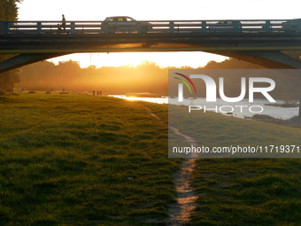 Cars and people are on the bridge across the Uzh River at sunset in Uzhhorod, Ukraine, on October 24, 2024. (