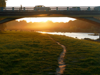 Cars and people are on the bridge across the Uzh River at sunset in Uzhhorod, Ukraine, on October 24, 2024. (