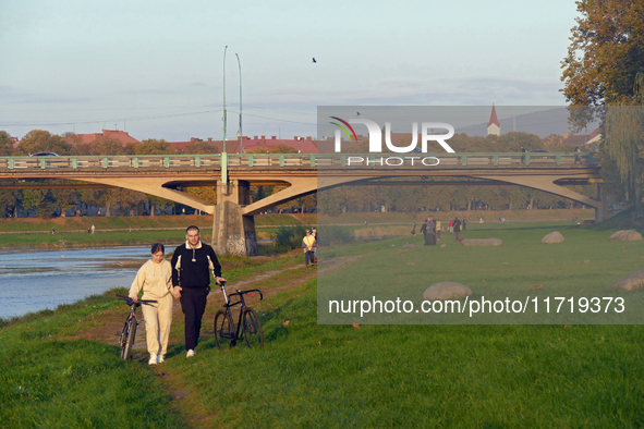 A man and woman push bicycles along a path running by the Uzh River in Uzhhorod, Ukraine, on October 27, 2024. NO USE RUSSIA. NO USE BELARUS...