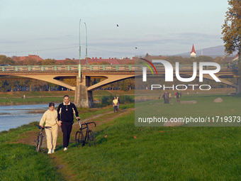 A man and woman push bicycles along a path running by the Uzh River in Uzhhorod, Ukraine, on October 27, 2024. NO USE RUSSIA. NO USE BELARUS...