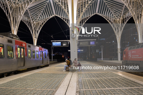 Two people with suitcases sit waiting for the arrival of a train on one of the platforms of Oriente railway station in Lisbon, Portugal, on...