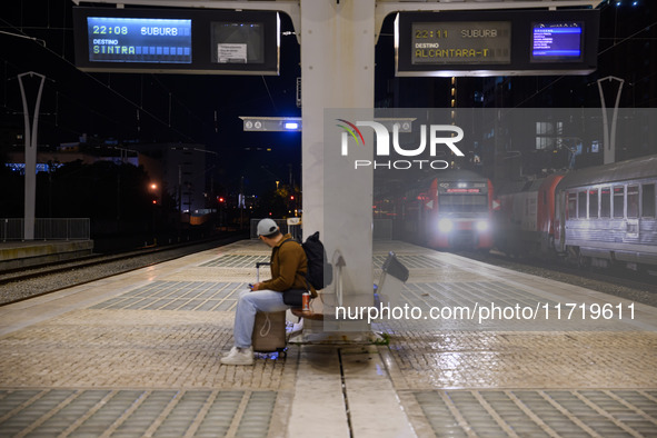 A person with suitcases sits waiting for the arrival of a train on one of the platforms of Oriente railway station in Lisbon, Portugal, on O...