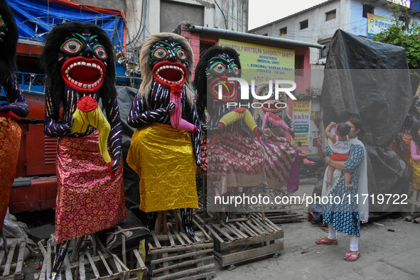 A mother and child stand beside displayed figurines of demons at a porters hub in Kolkata, India, on October 29, 2024, ahead of the Hallowee...