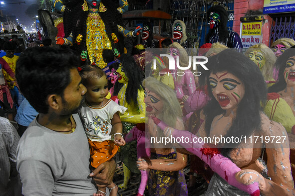 A father and child stand beside displayed figurines of demons at a porters hub in Kolkata, India, on October 29, 2024, ahead of the Hallowee...