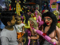 A father and child stand beside displayed figurines of demons at a porters hub in Kolkata, India, on October 29, 2024, ahead of the Hallowee...