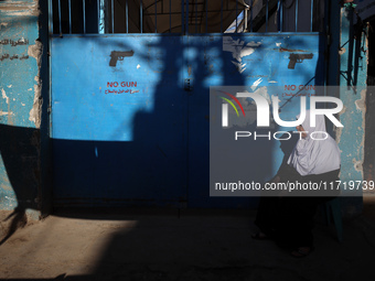 A Palestinian woman sits in front of a gate at the UNRWA (United Nations Relief and Works Agency) center at the Nuseirat refugee camp in the...