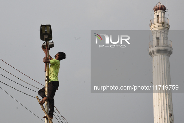 A worker repairs a defunct street light in front of an iconic monument in Kolkata, India, on October 29, 2024. 