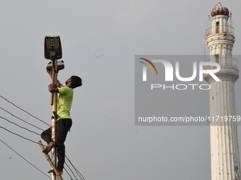 A worker repairs a defunct street light in front of an iconic monument in Kolkata, India, on October 29, 2024. (