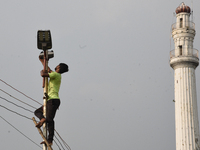 A worker repairs a defunct street light in front of an iconic monument in Kolkata, India, on October 29, 2024. (