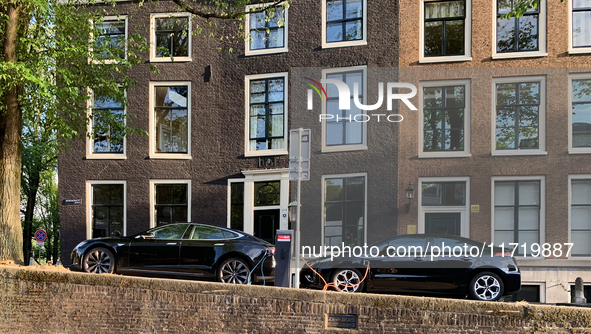 Two electric cars charge at a station located along a canal in central Amsterdam, Netherlands, on July 8, 2019. 